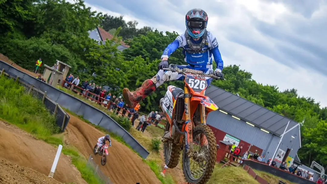 Motocrosskører hopper med motorcyklen på banen